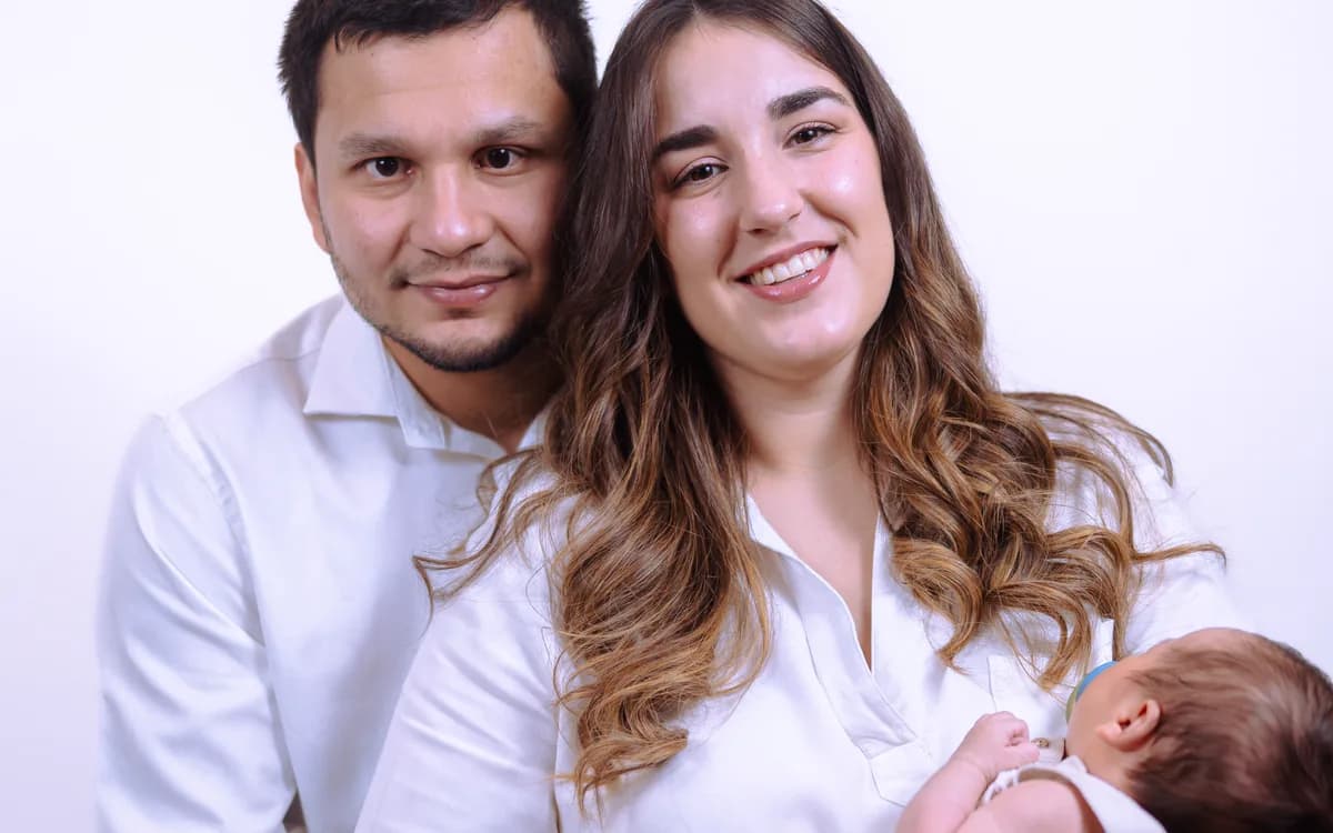 Pareja sonriendo mientras sostiene a su bebé